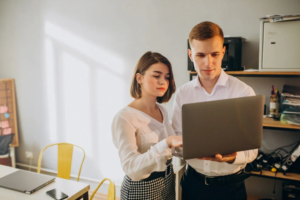 Deux jeunes au travail regardent l'ecran d'un ordinateur portable